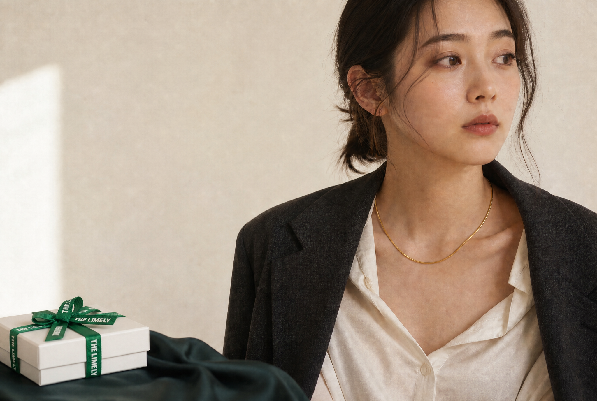 THE LIMELYのギフトボックスとスネークチェーンネックレスを身につけたモデル